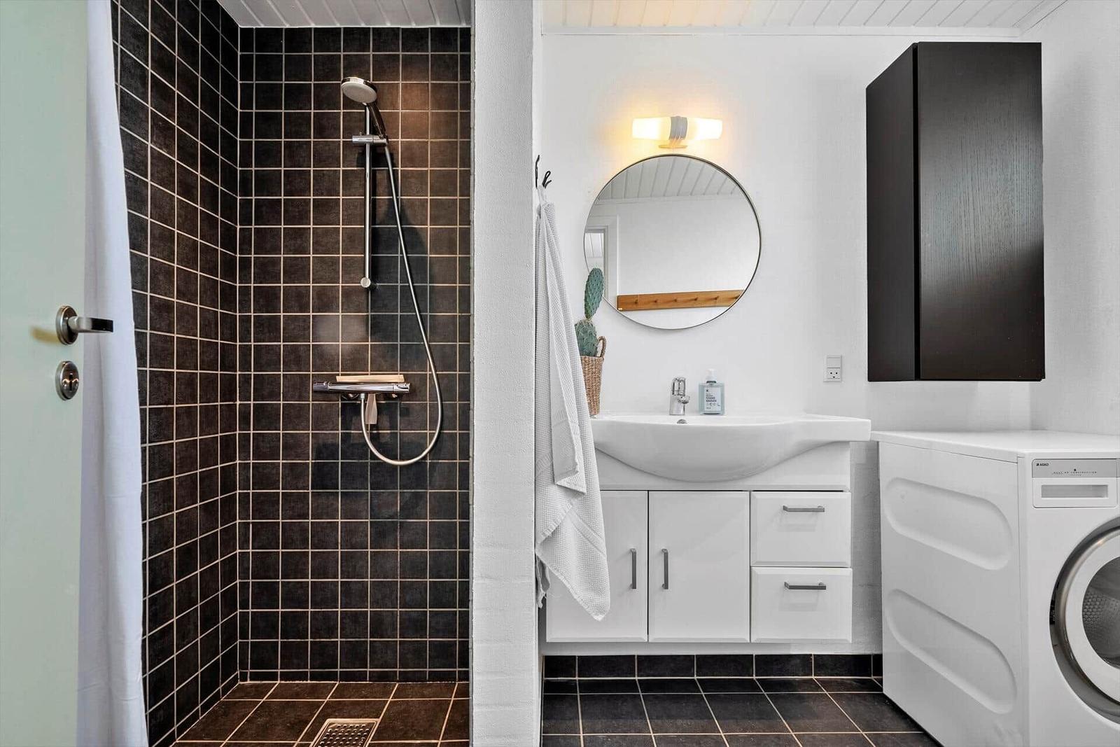 Bad mit Dusche, Waschbecken und Waschmaschine.