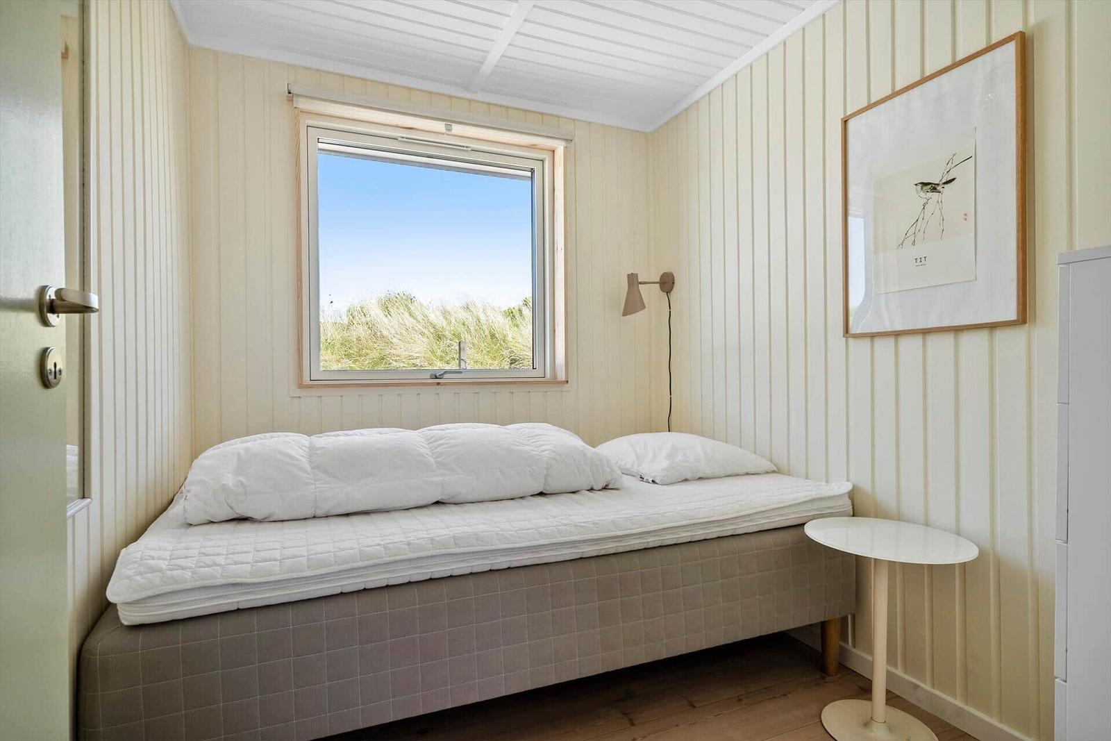 Schlafzimmer mit Bett, Fenster und Wandbild.