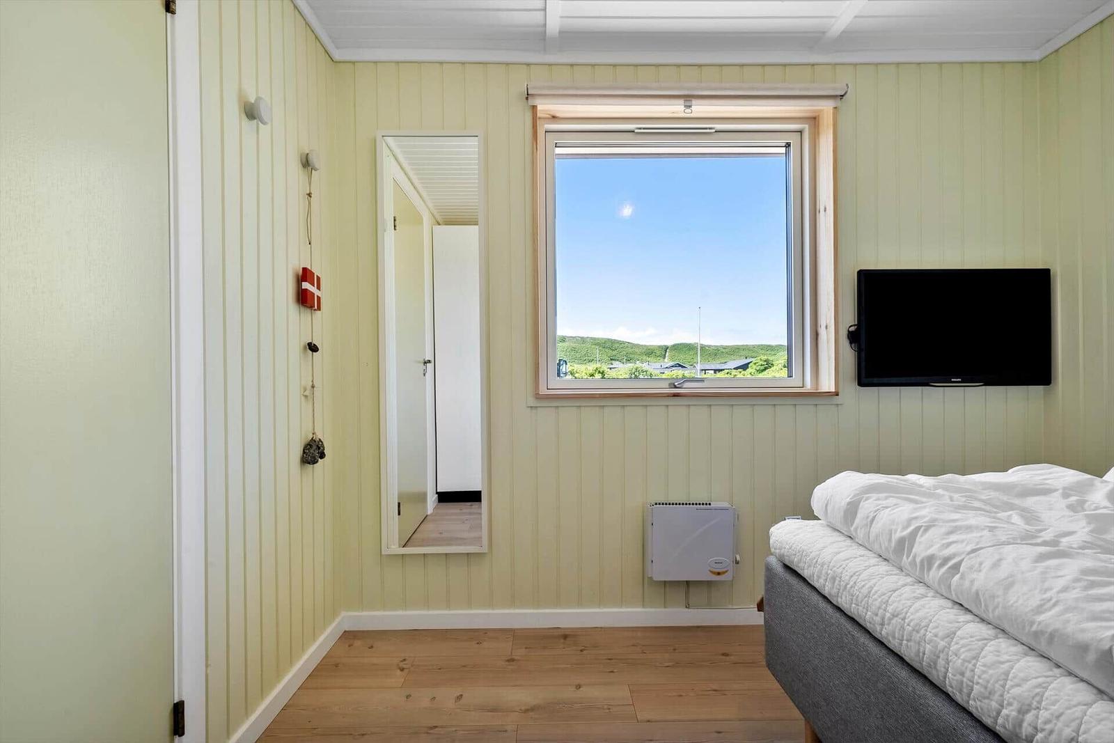 Schlafzimmer mit Fenster, Bett und Fernseher an der Wand.
