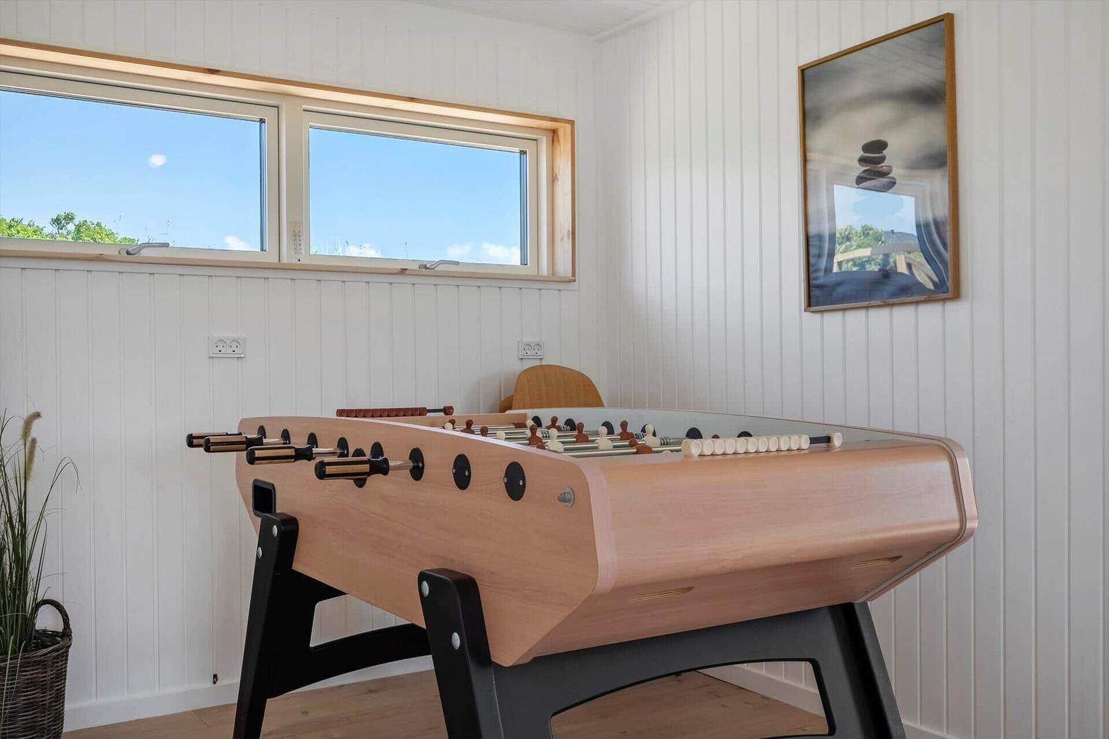 Fussballtisch in einem Raum mit Fenstern und Wandbild.