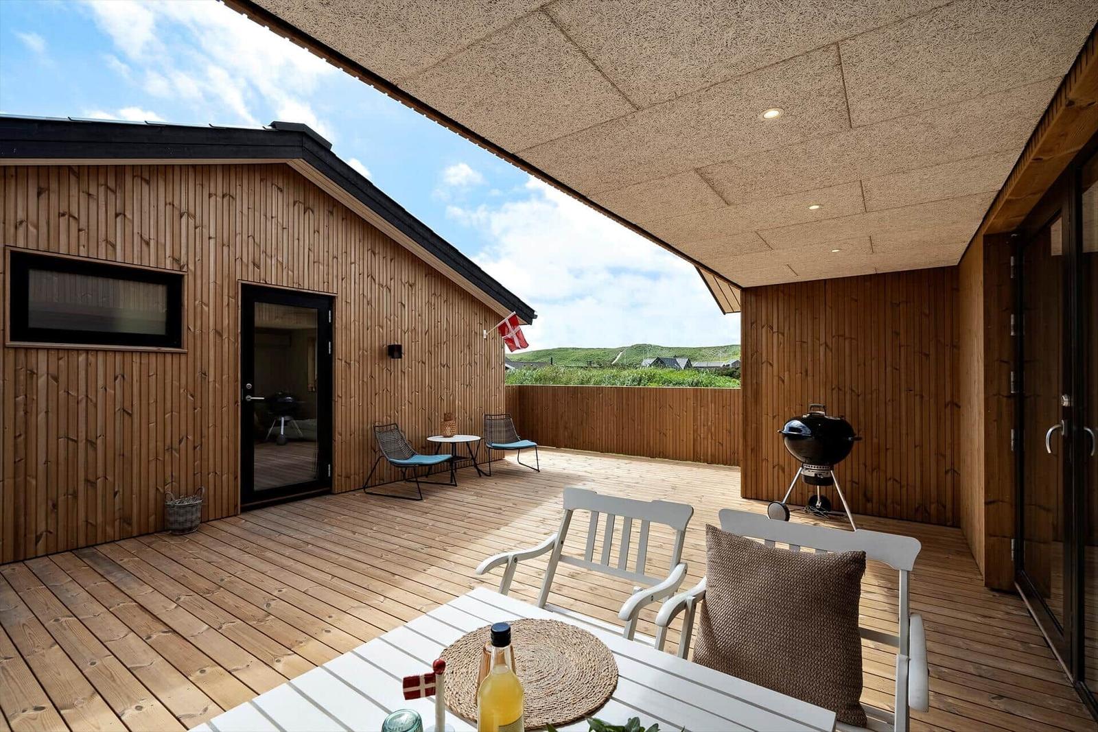 Terrasse mit Sitzgelegenheiten, Grill und Blick auf die Landschaft.