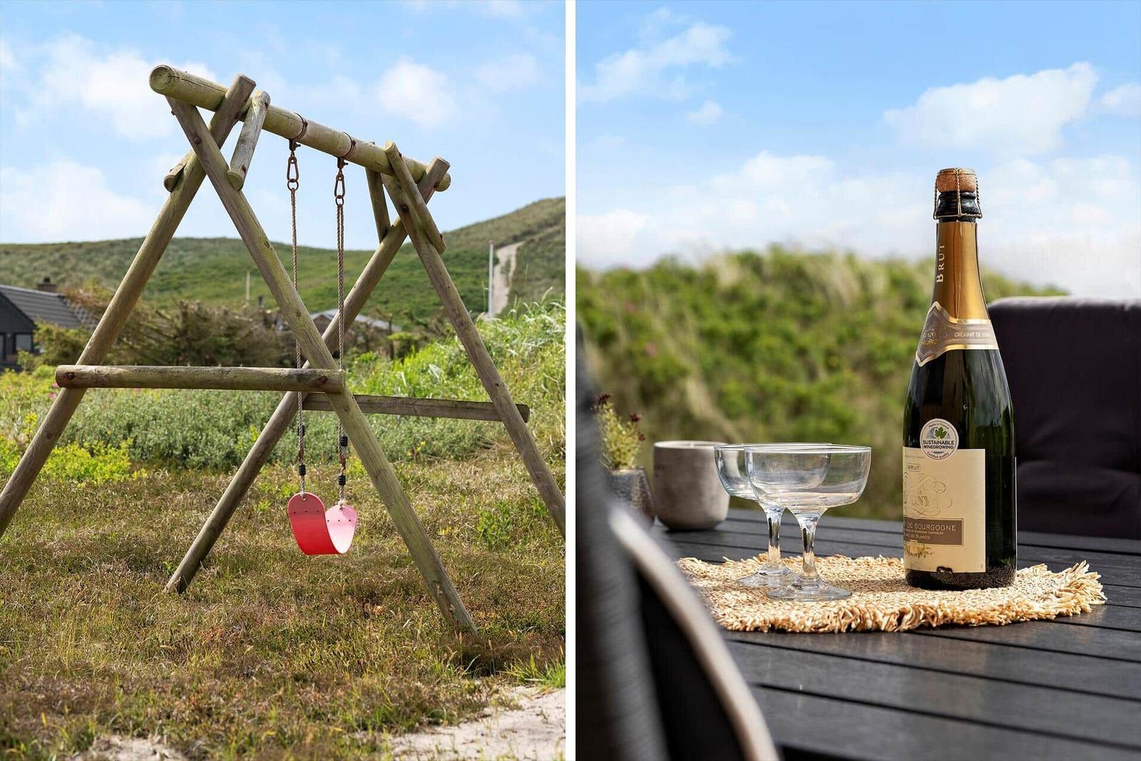 Holzschaukel im Gras und Champagner auf Terrasse mit Blick auf Hügel
