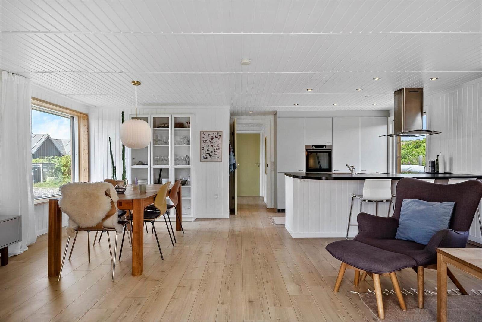 Moderne Küche mit Essbereich und Sitzgelegenheit. Holzboden und weiß gestrichene Wände.