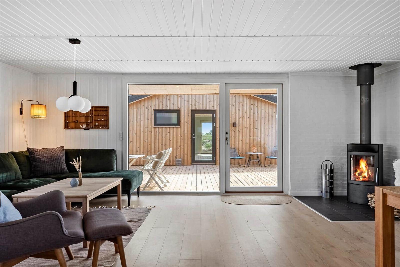 Wohnraum mit Kamin, Sofa und Terrasse