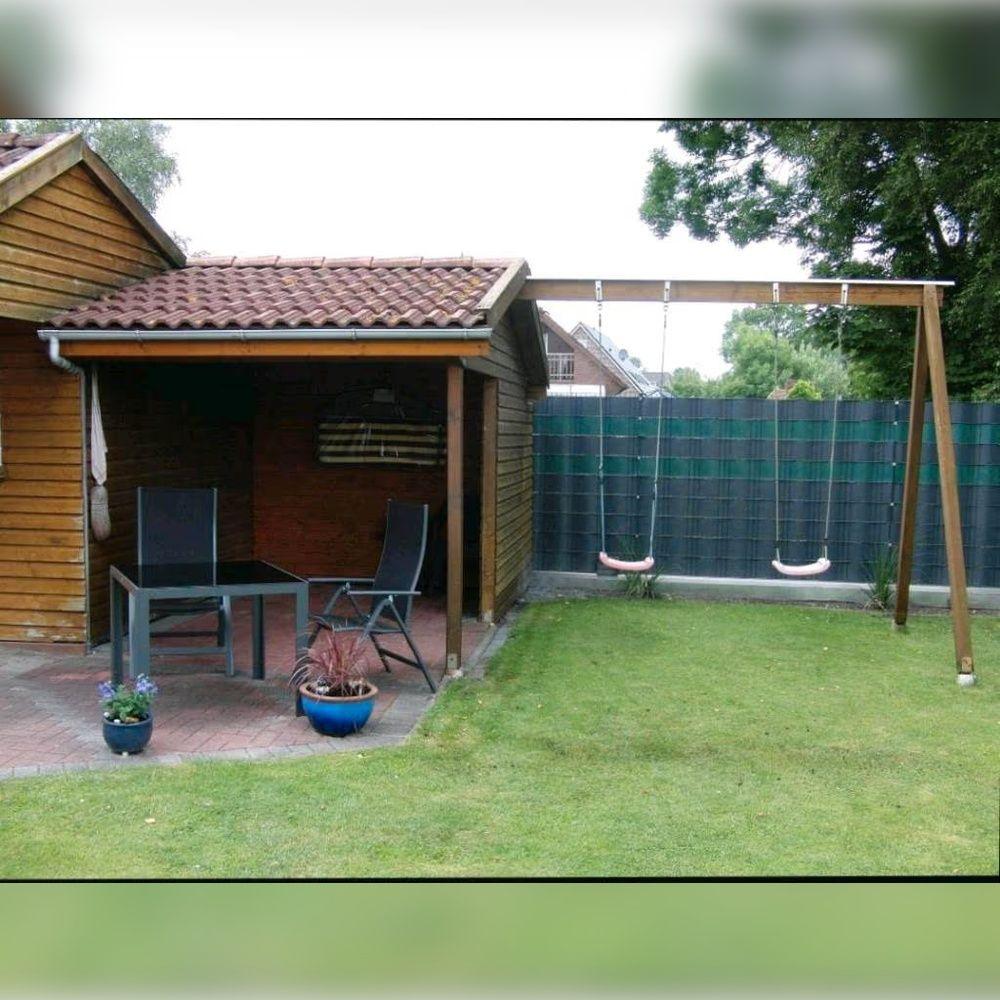 Hinterhof mit Terrasse, Schaukel und grünem Rasen.