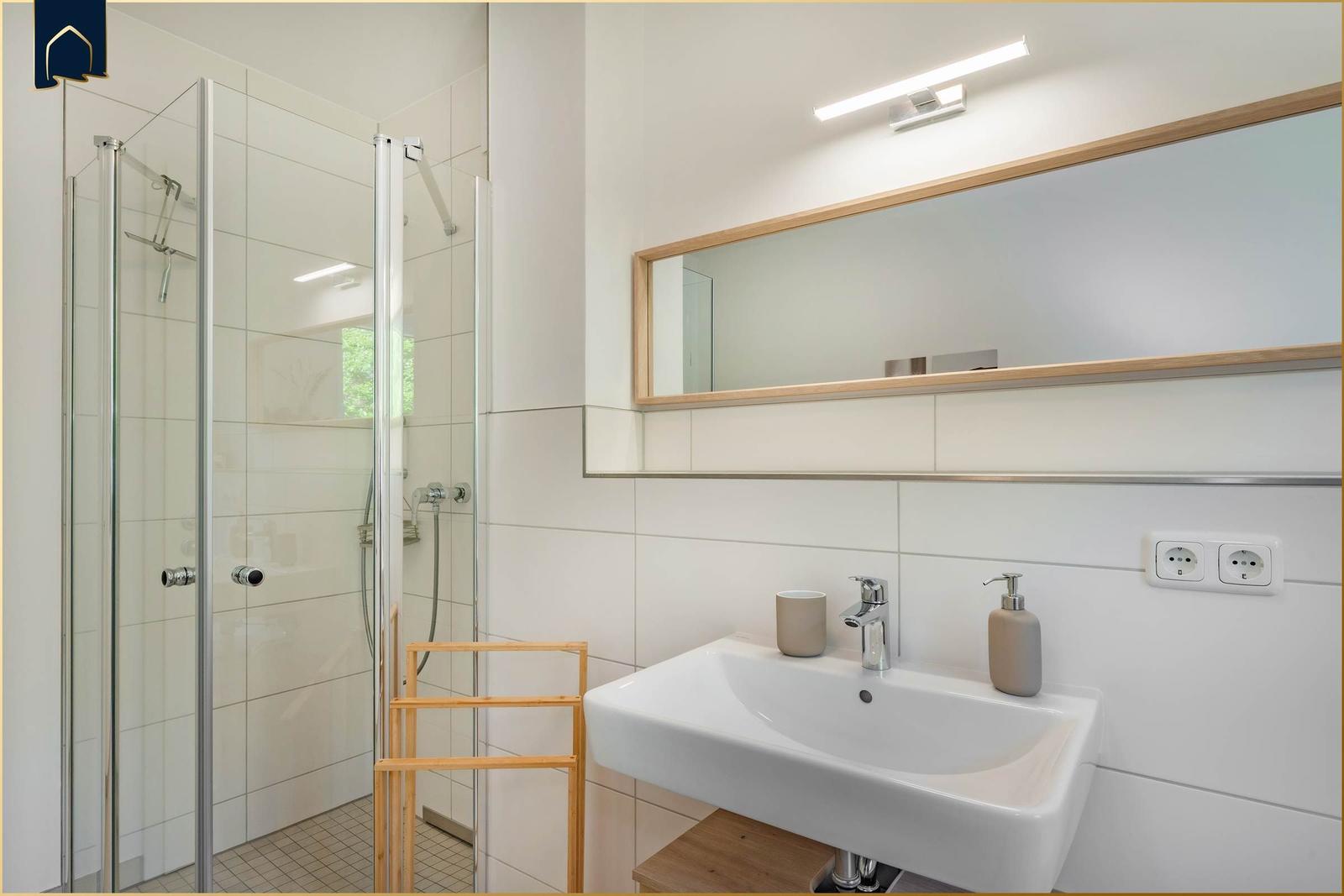 Badezimmer mit Dusche, Waschbecken und Spiegel.