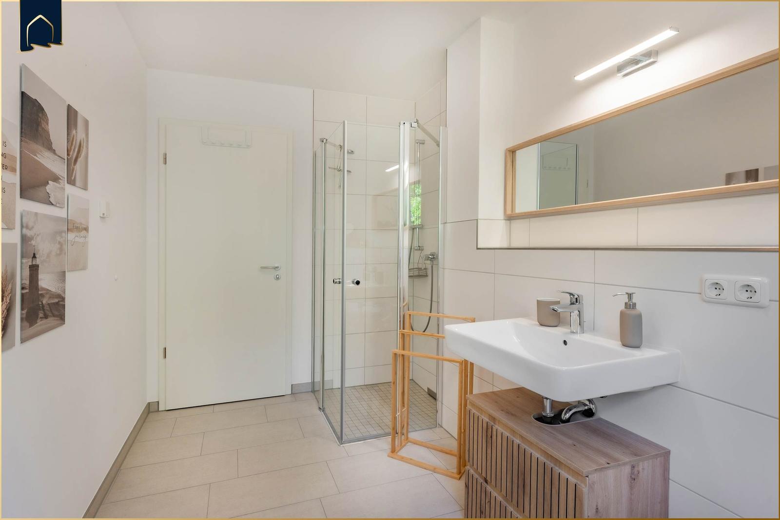 Badezimmer mit Dusche, Waschbecken und Spiegel.