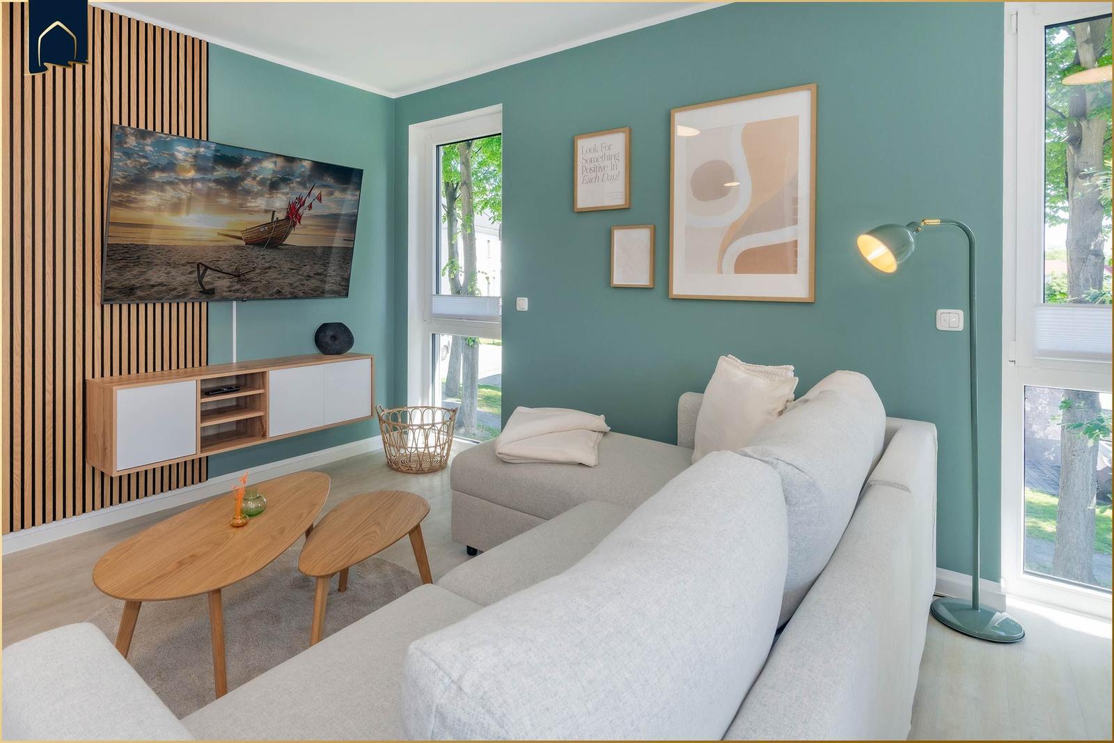 Wohnzimmer mit Sofa, TV und Fenstern