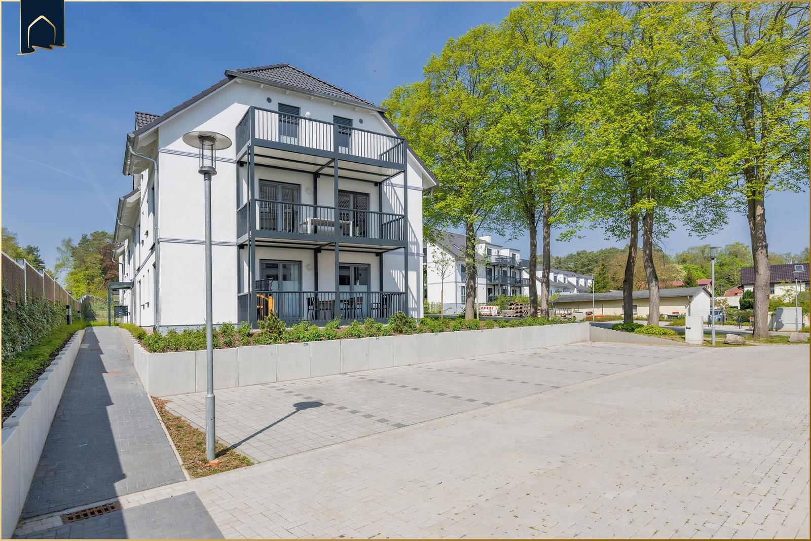 Modernes Mehrfamilienhaus mit Balkonen und gepflastertem Hof.