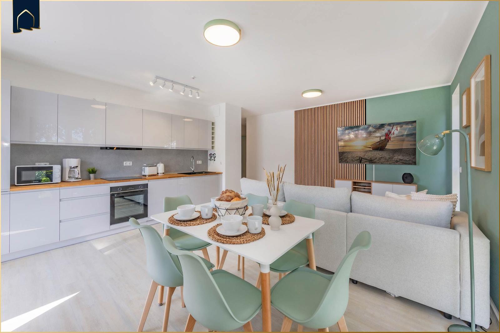 Moderne Küche mit Essbereich und Wohnzimmer mit Sofa und Fernseher.