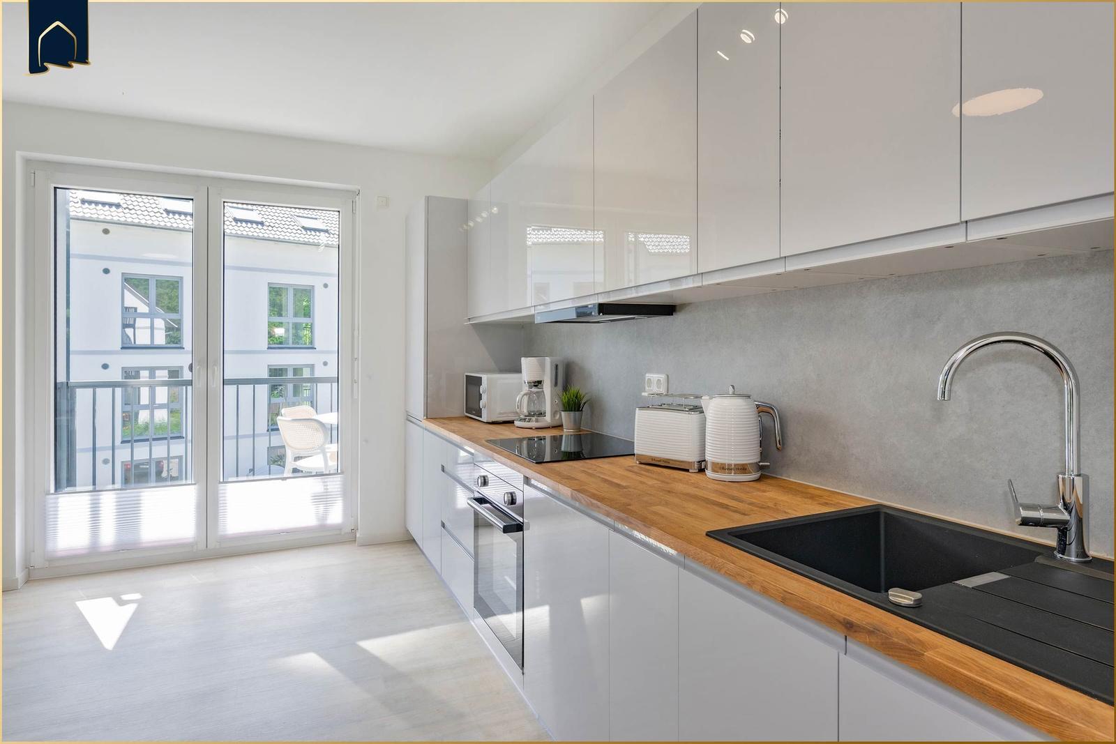 Moderne Küche mit Holz-Arbeitsplatte und Balkonansicht.