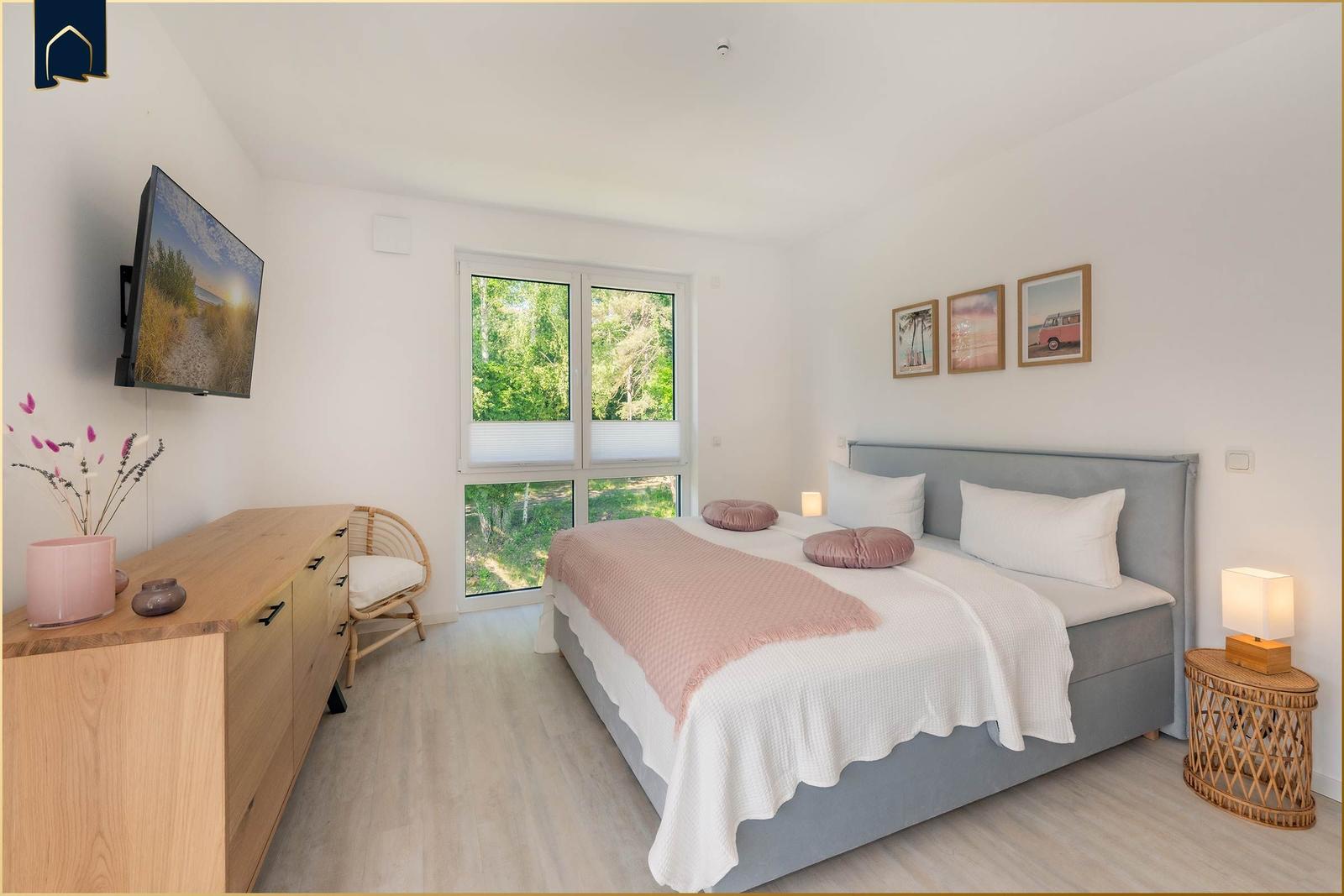 Schlafzimmer mit Bett, Fenster und TV.