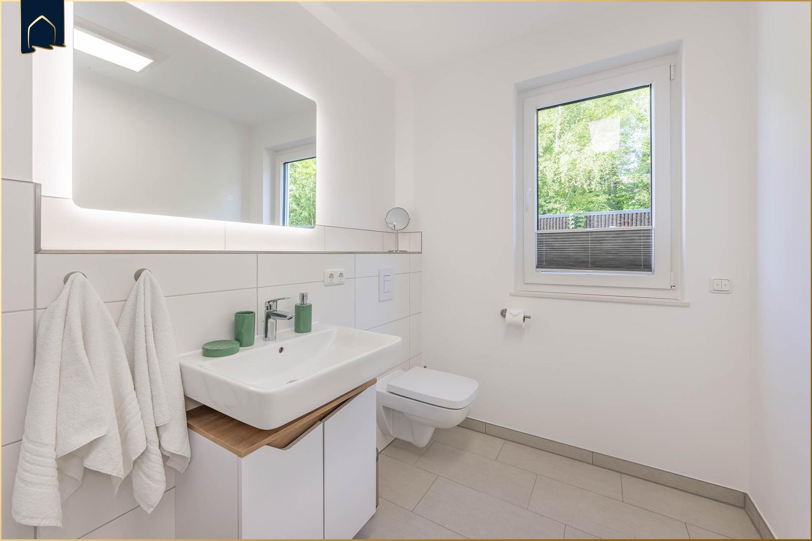 Badezimmer mit Waschbecken, Spiegel und Fenster zur Außenseite.