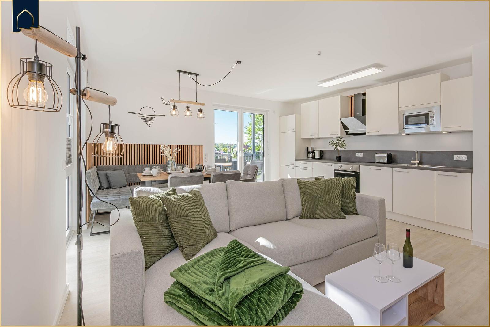 Wohnzimmer mit Sofa, Küchenbereich und Balkonansicht.