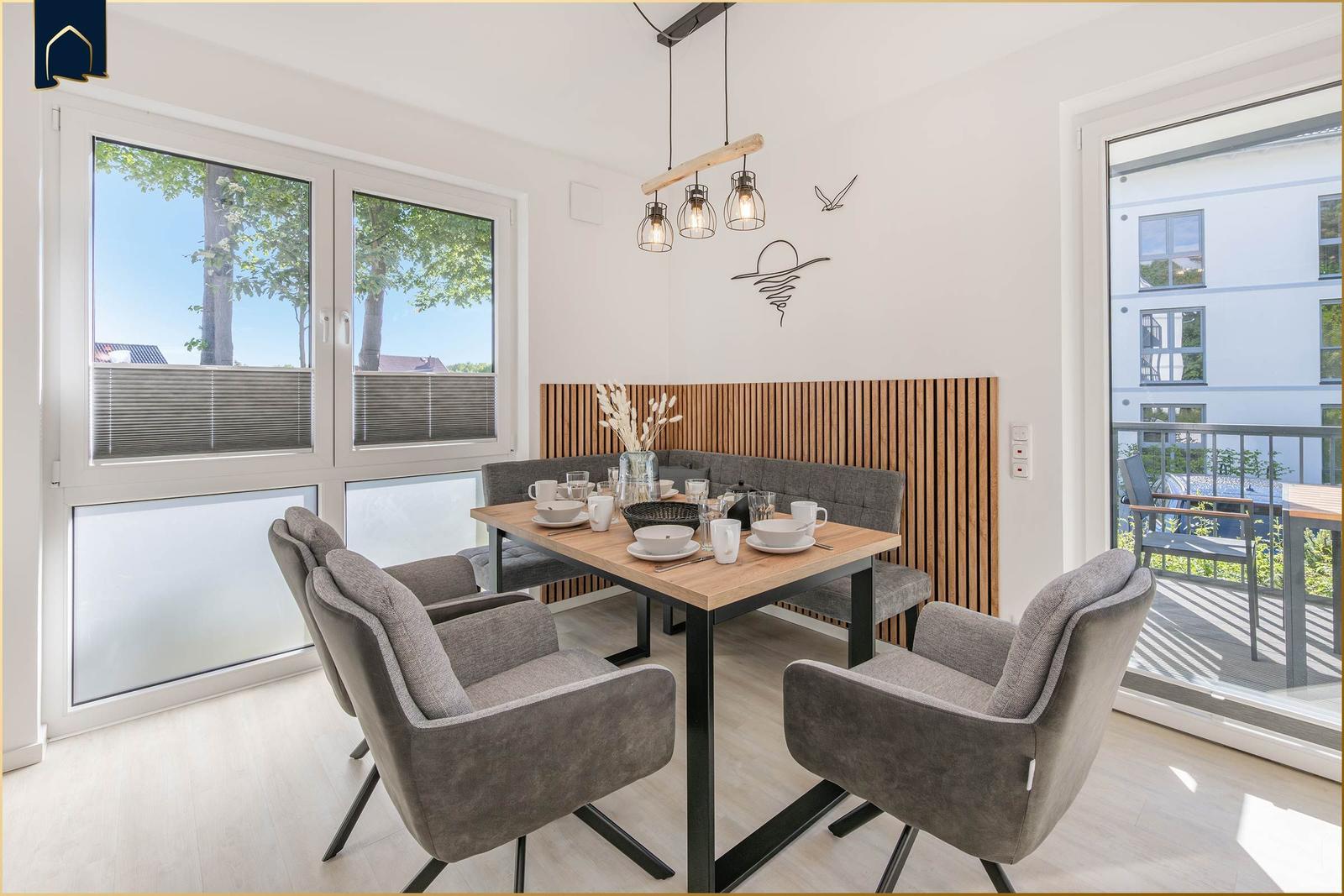 Esszimmer mit Tisch, Stühlen und Blick auf Balkon.