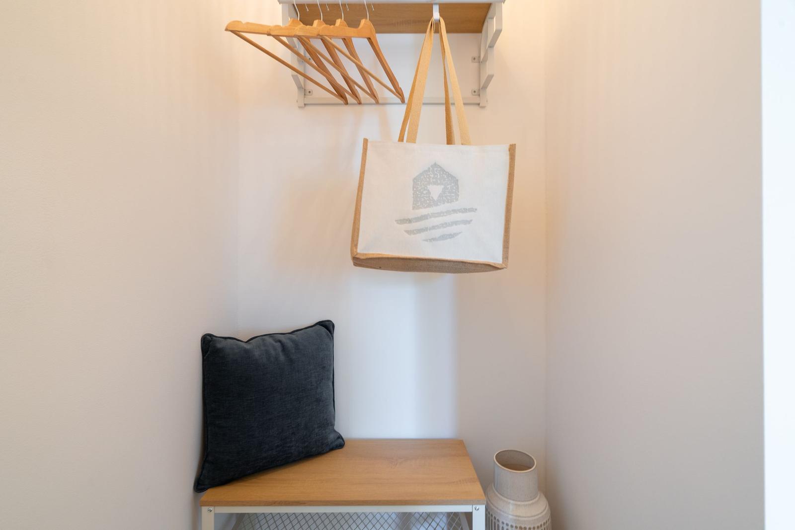 Hängende Tasche und Kleiderhaken über einem Holztisch mit Kissen.