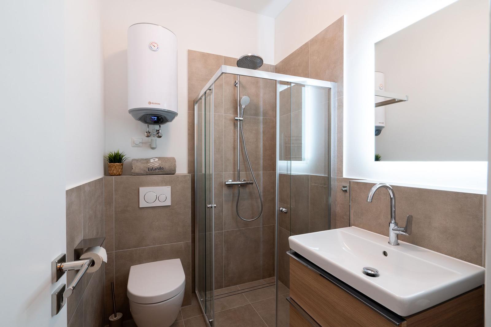 Badezimmer mit Dusche, Waschbecken und Toilette. Moderne Einrichtung.