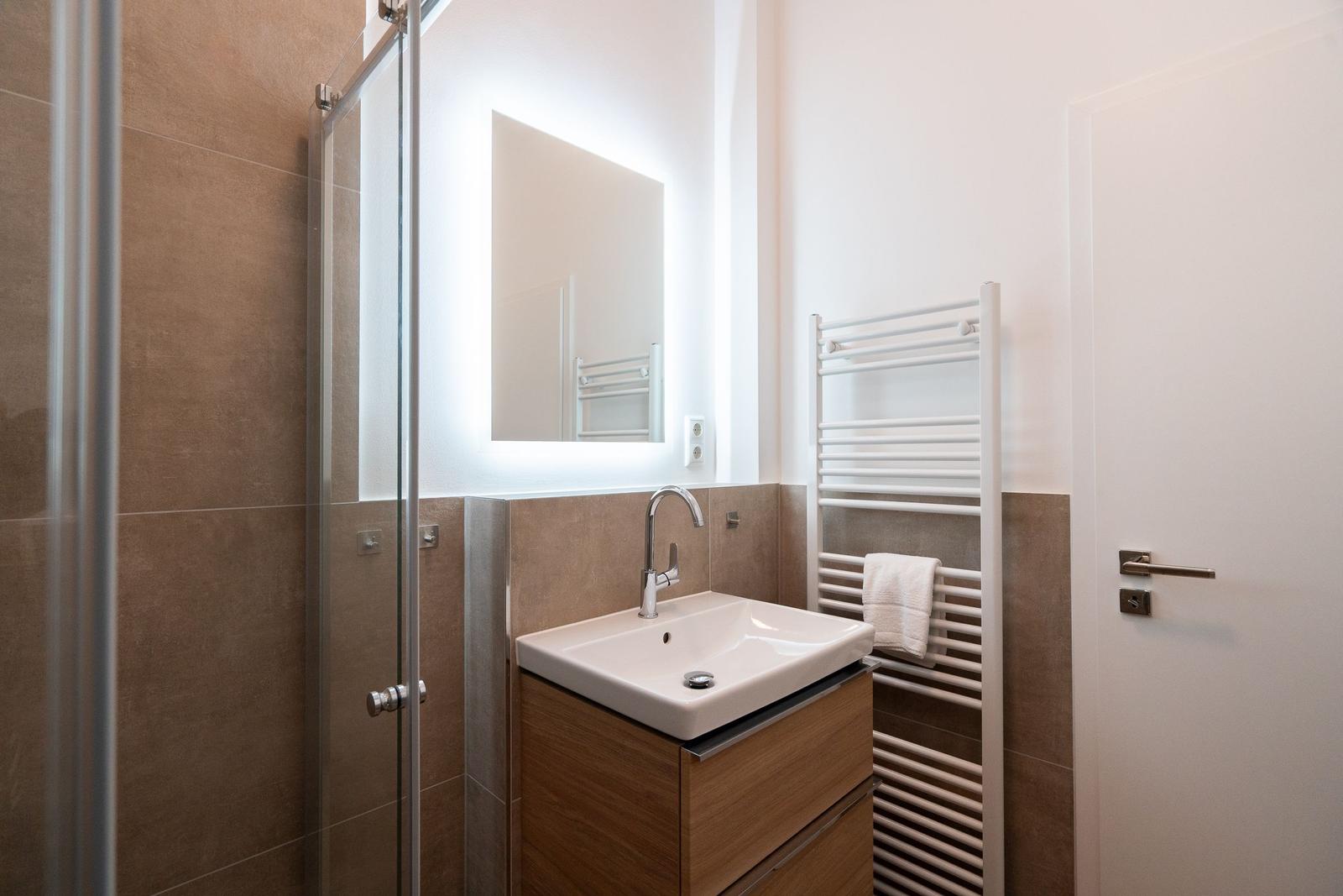 Badezimmer mit Dusche, Waschbecken und Handtuchhalter.