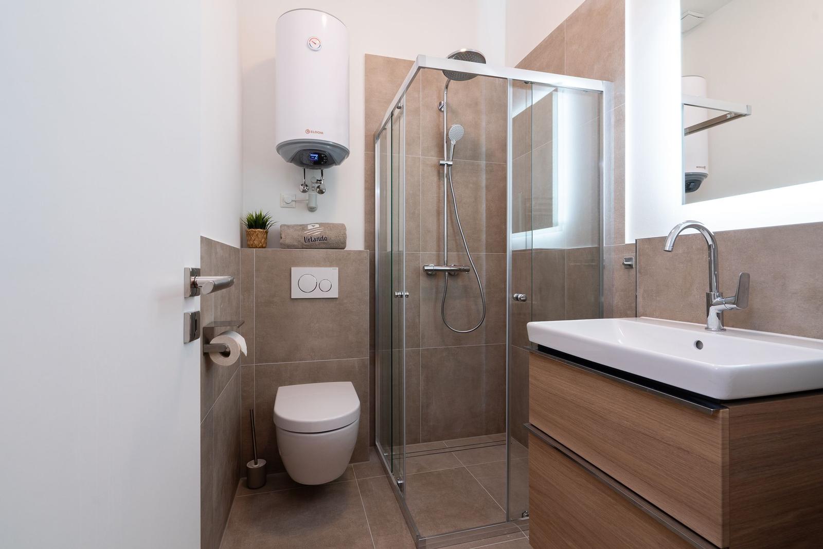 Badezimmer mit Dusche, Waschbecken und Toilette.