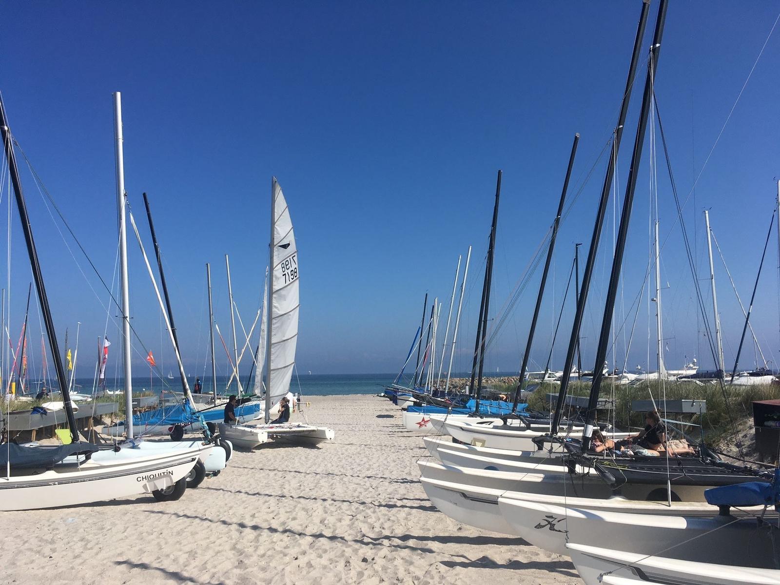 Sailboats stehen auf Sandstrand vor Meer unter blauem Himmel