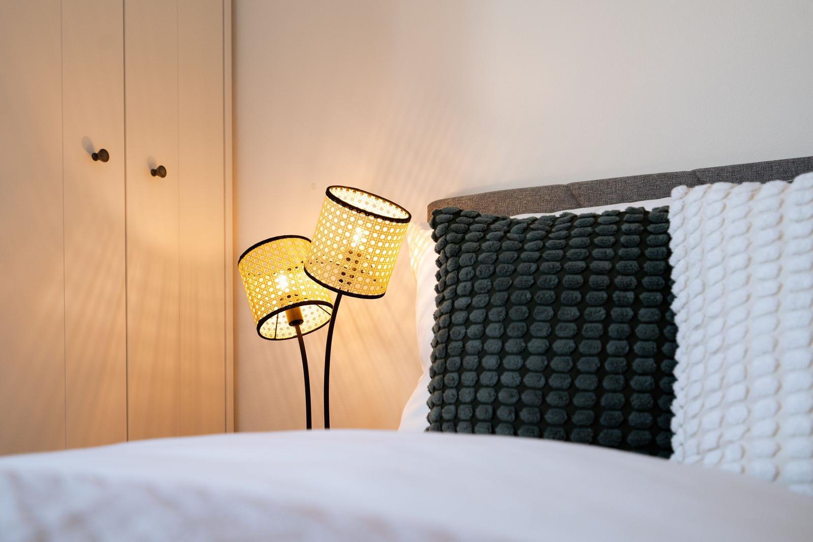 Bettkopf mit Kissen, Stehlampe und Schrank im Schlafzimmer