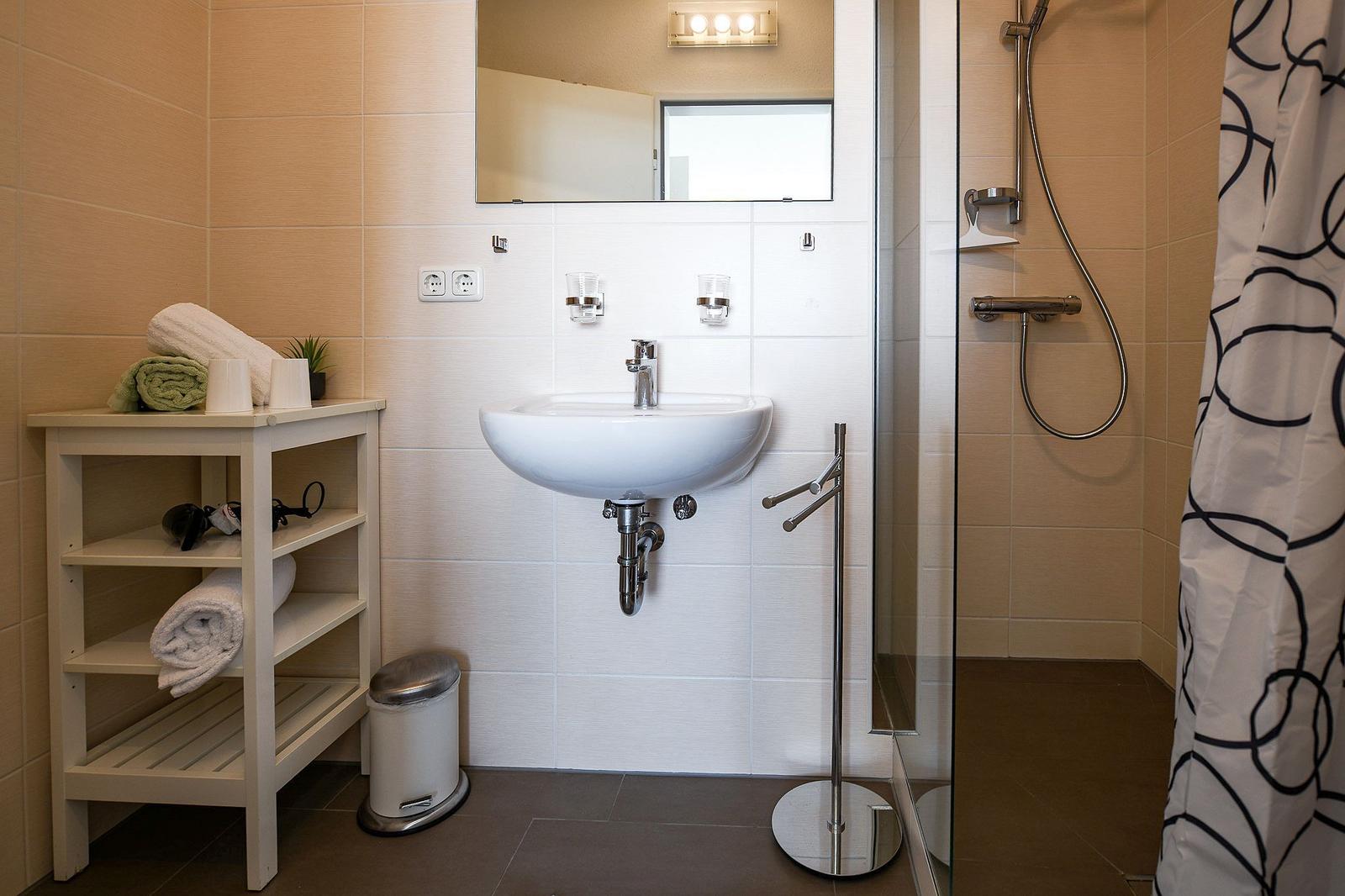 Badezimmer mit Dusche, Waschbecken und Handtuchständer.