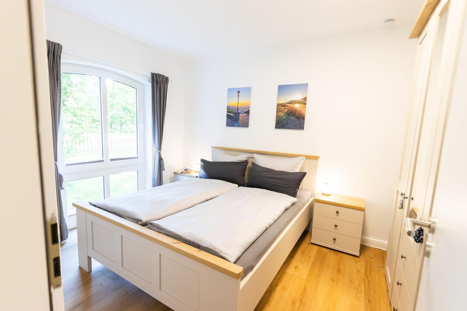 Schlafzimmer mit Doppelbett, Fenster und Nachttischen.