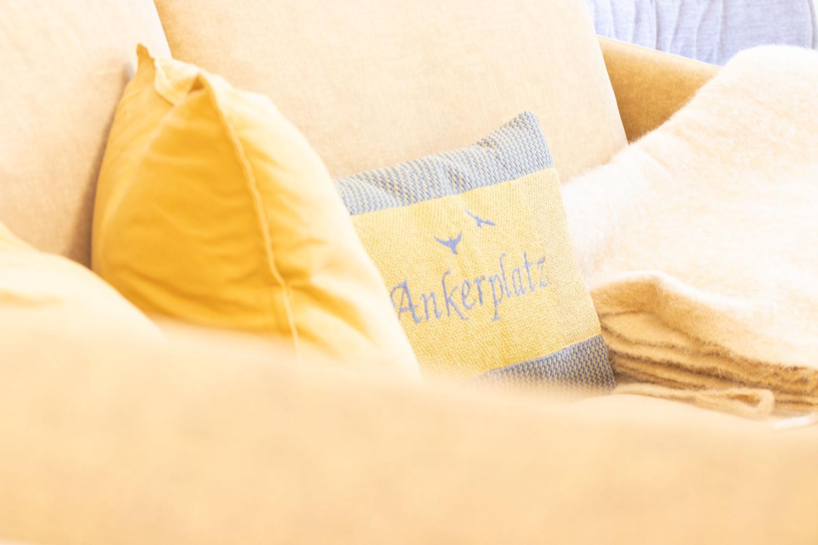 Sofa mit Kissen und Decke, eines mit Aufschrift Ankerplatz.
