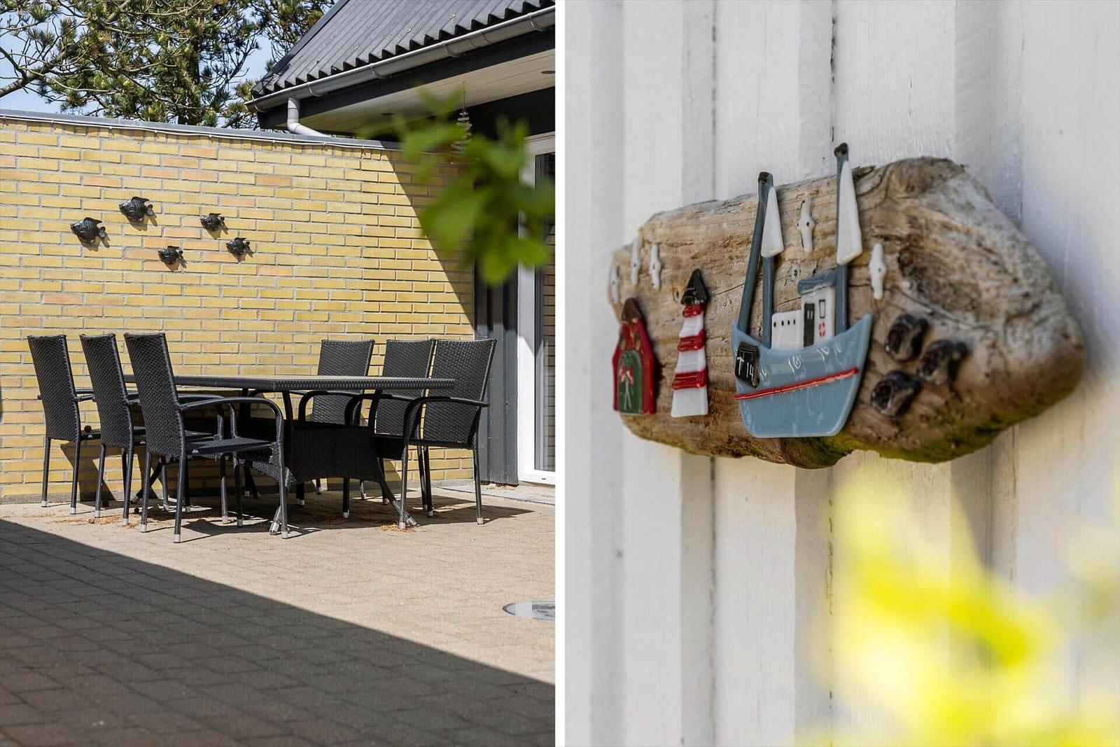Terrasse mit Tisch und Stühlen vor gelbem Mauerwerk. Holzdekoration mit Boot und Leuchtturm an Wand.