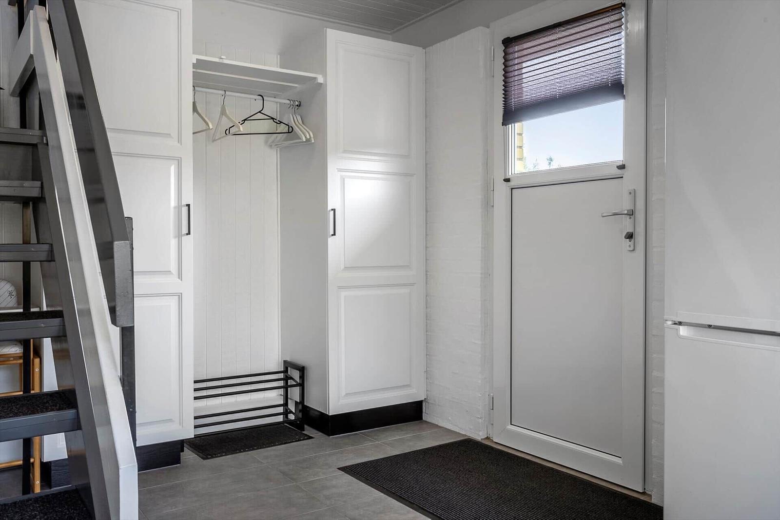 Eingangsbereich mit Kleiderschrank, Tür und Stufen zur oberen Etage.