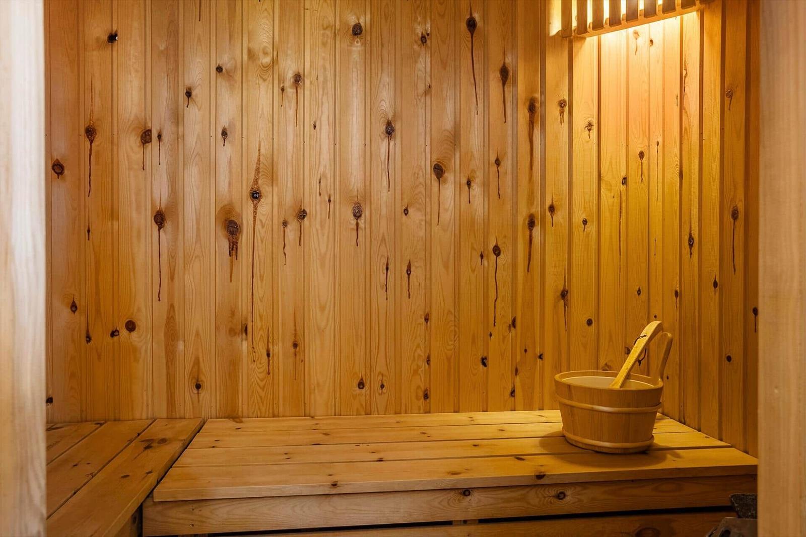 Holzsauna mit Sitzbank und Eimer mit Kelle.