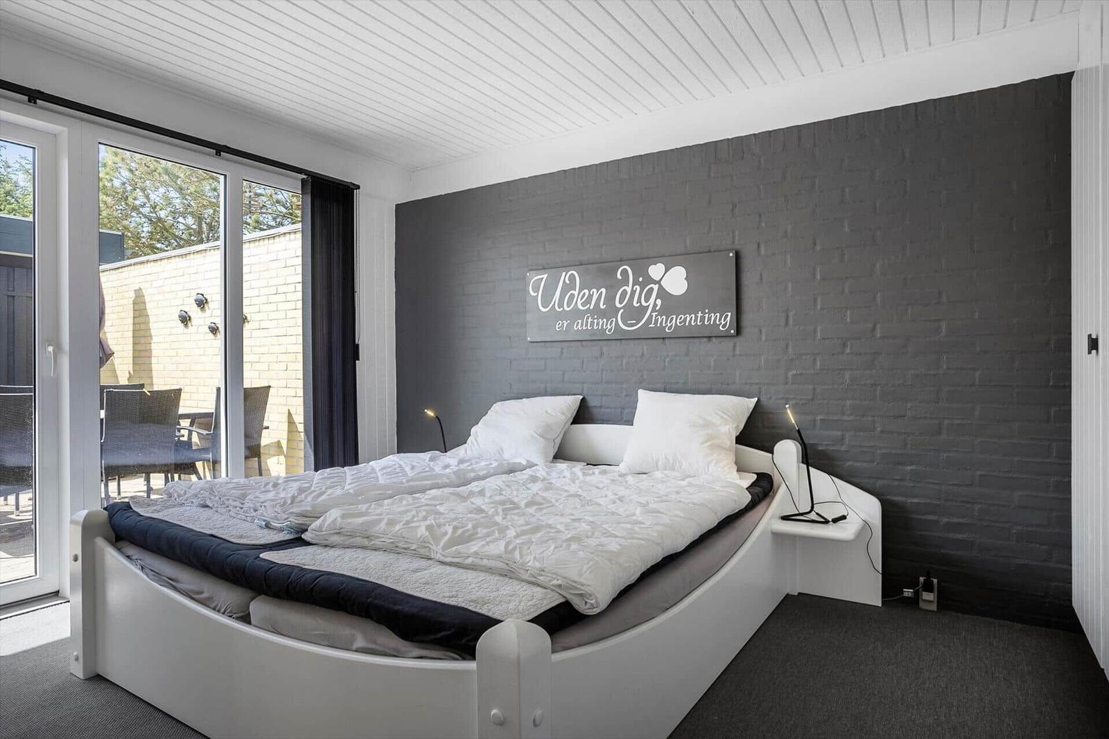 Schlafzimmer mit Bett, Glasfront und Wanddekoration.