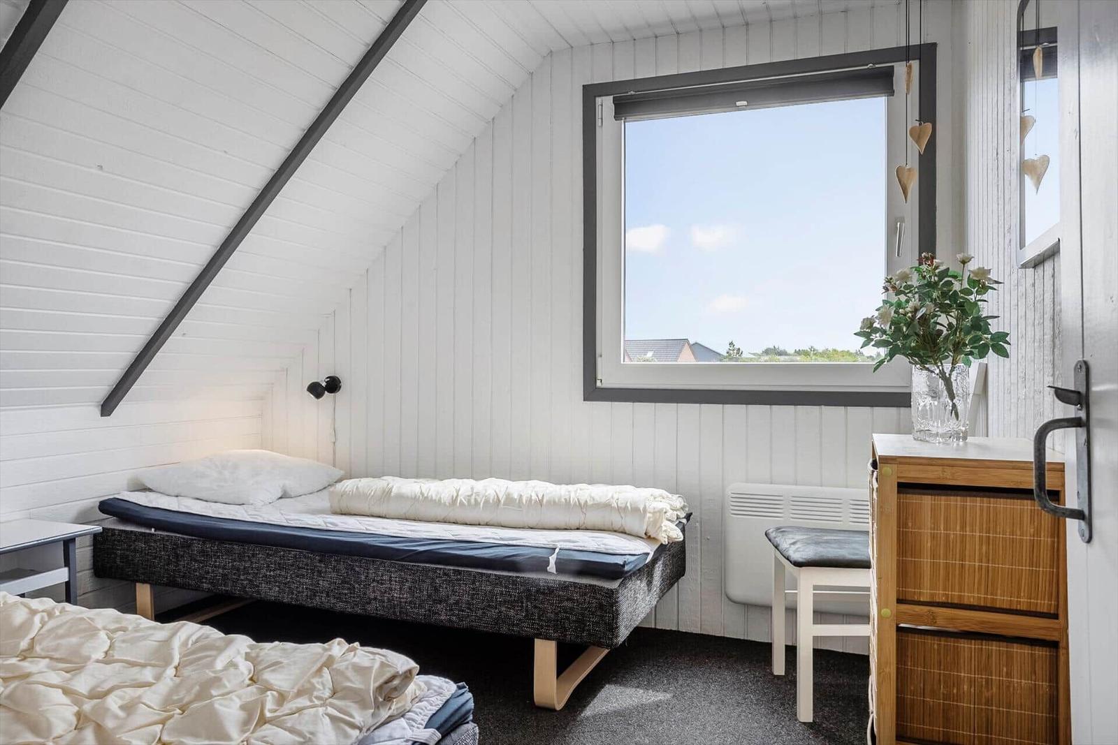 Schlafzimmer mit Dachschräge, Fenster und Bett.