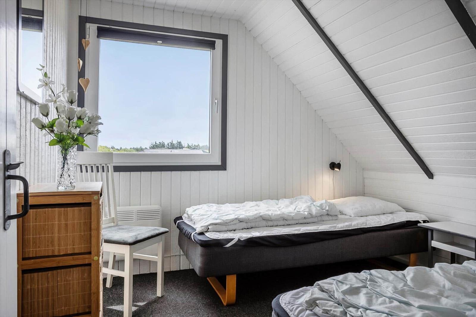 Schlafzimmer mit Dachschräge, Bett und Fenster mit Blick.