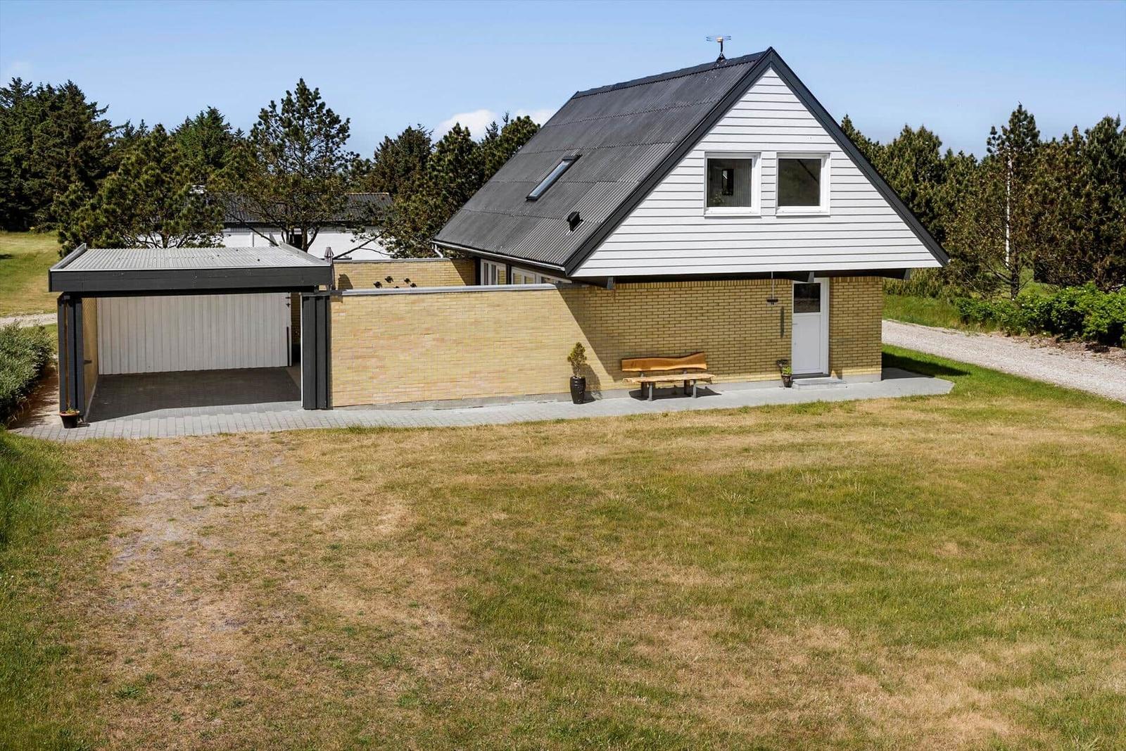 Moderne Villa mit Garage und Garten. Holzbank vor Eingang.