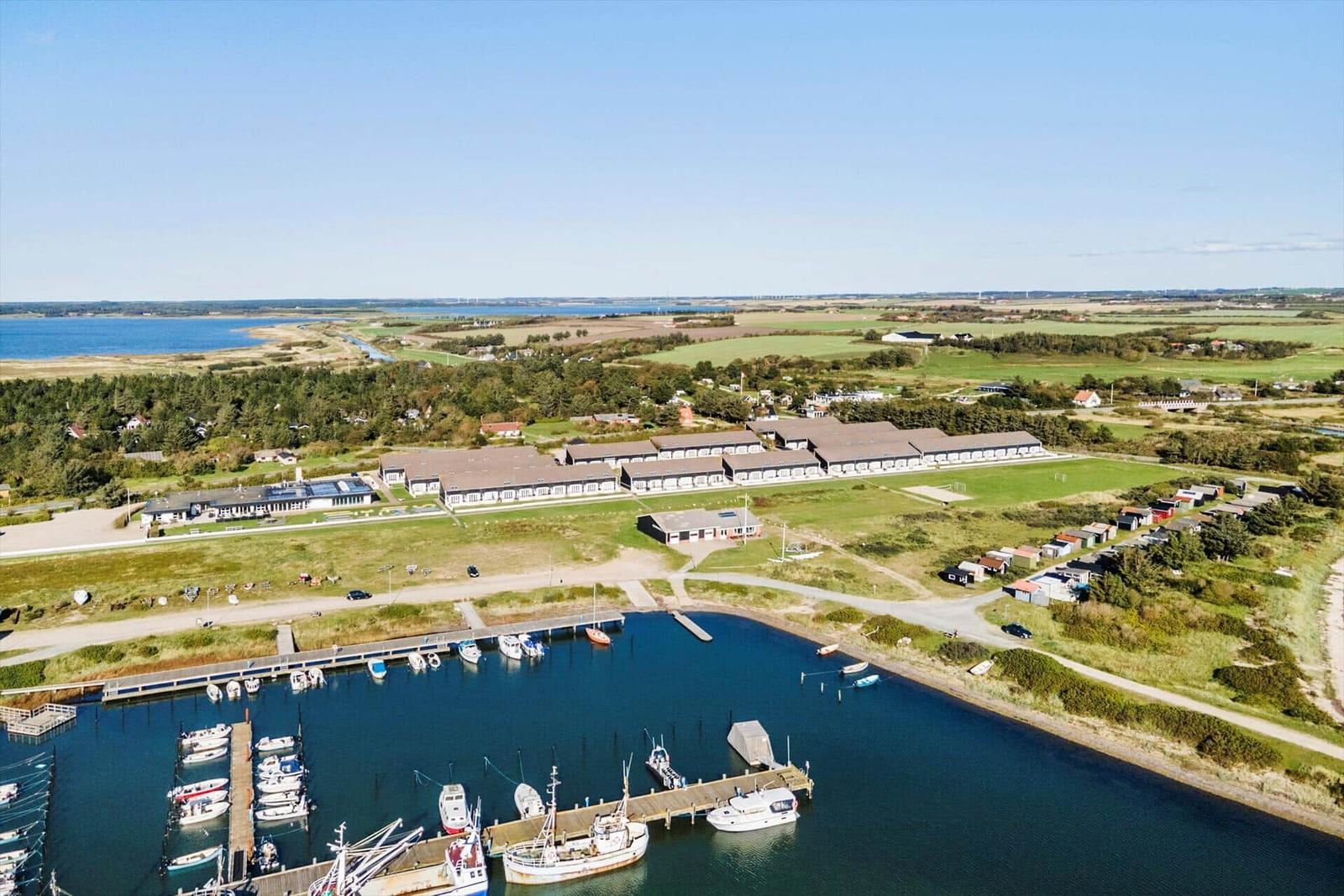 Hafen mit Booten, moderne Gebäude und grüne Landschaft im Hintergrund.