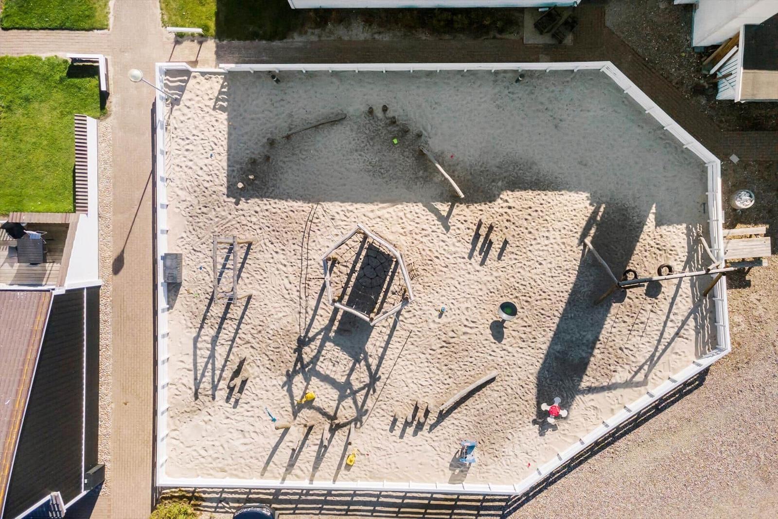 Großer Sandplatz mit Spielgeräten und Kinderspielzeug.