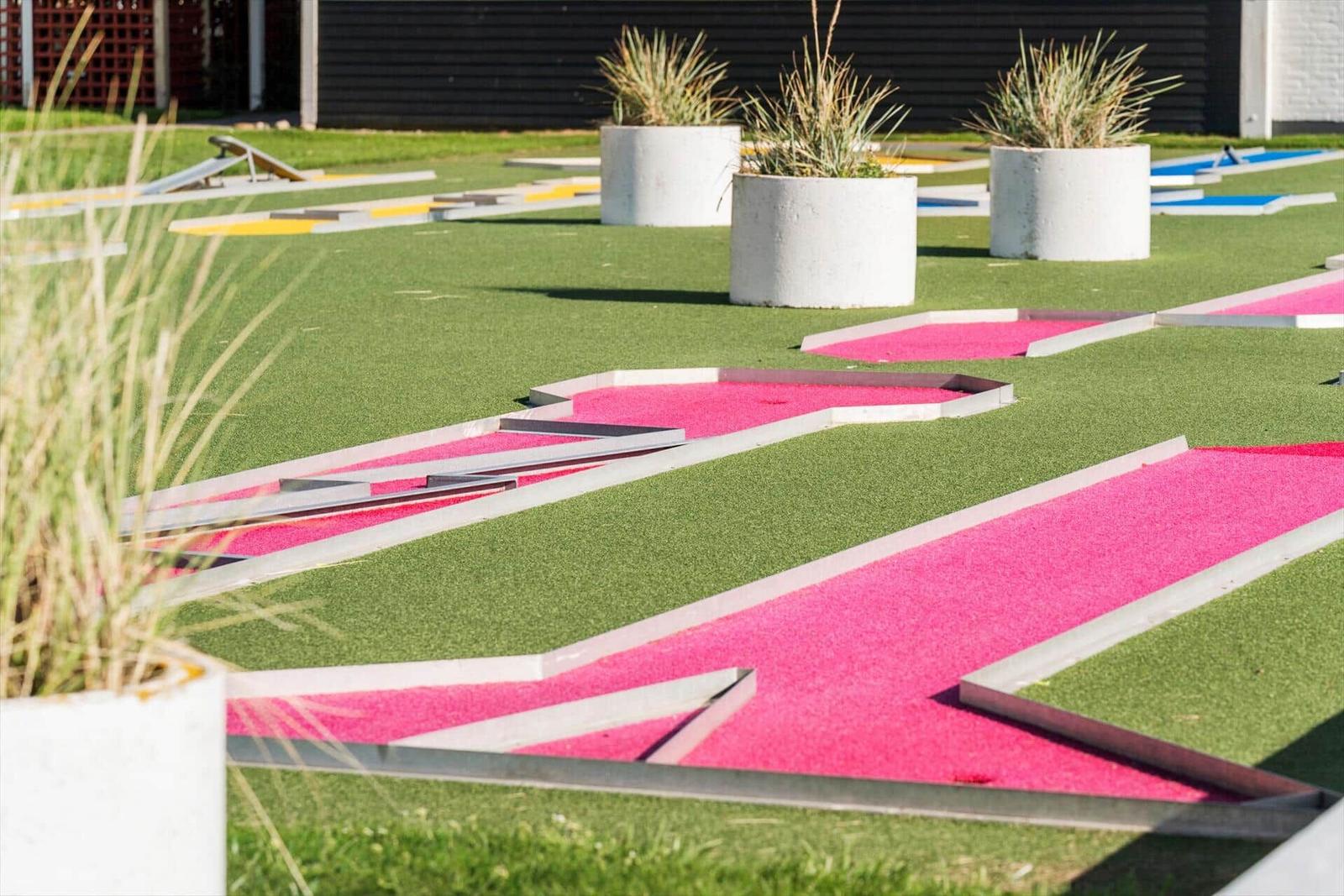 Minigolfplatz mit grünem Rasen und pinken Bahnen