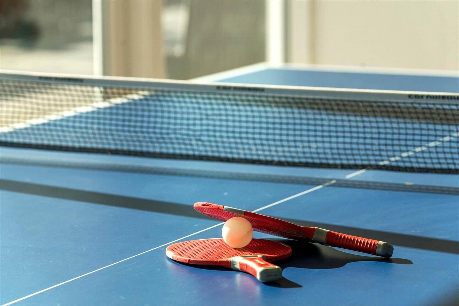 Tischtennisplatte mit Schlägern und Ball. Spielbereich im Innenbereich.