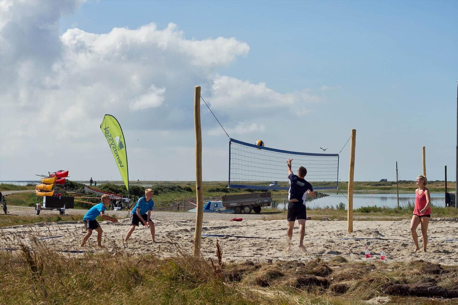 Gruppe spielt Strandvolleyball an einem sonnigen Tag am Ufer.