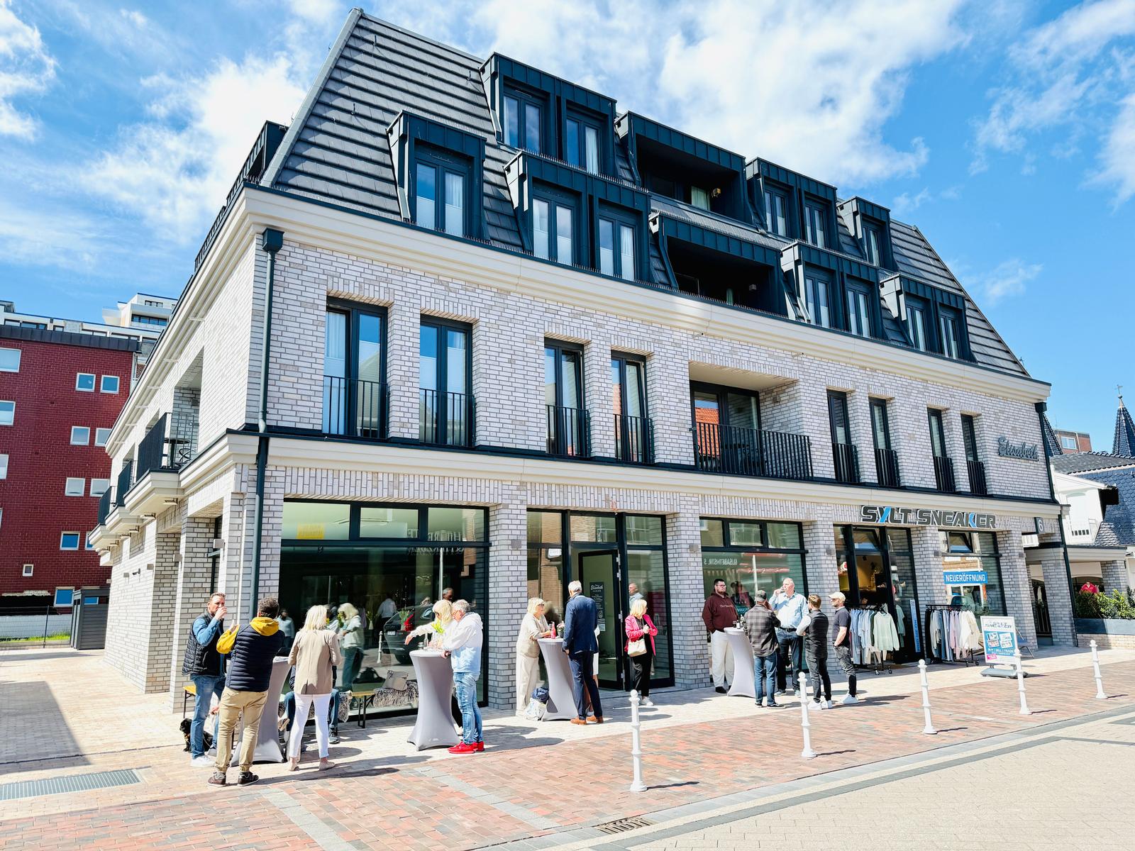 Moderne Fassade mit Geschäften und Gästen auf der Straße.