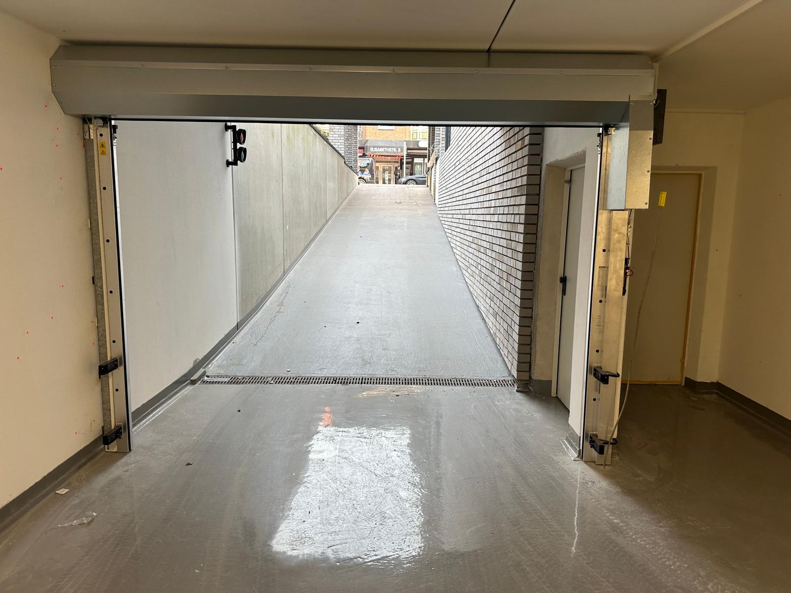 Garage mit Rolltor und Blick auf eine Straße mit Backsteinmauer