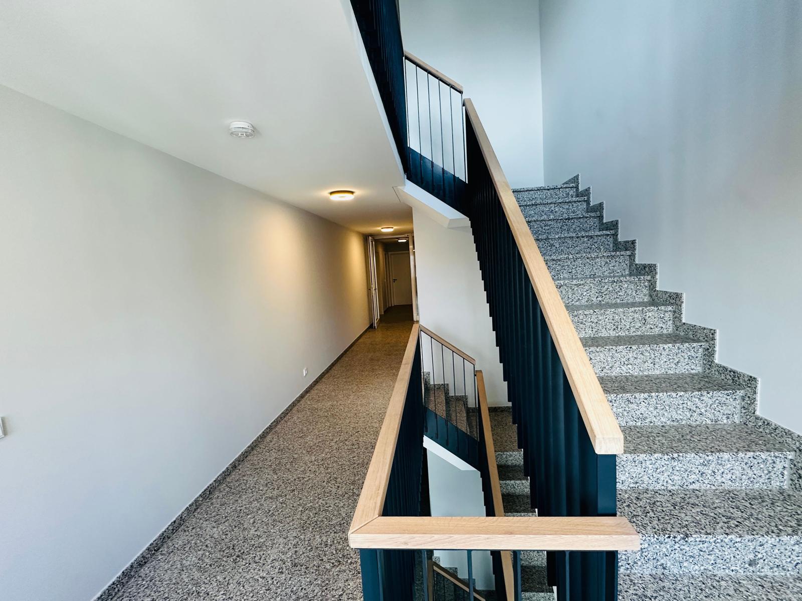 Treppe mit Steinstufen und Holzgeländer führt zur oberen Etage.