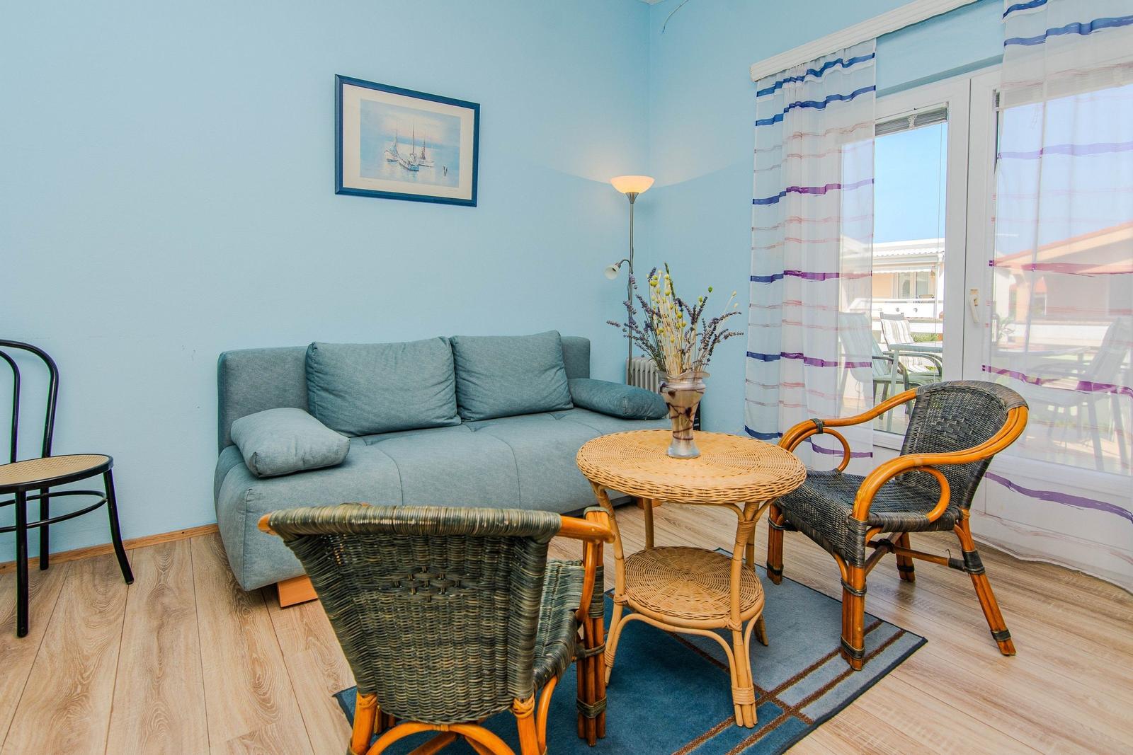 Living room with sofa, two chairs and table. Access to terrace.