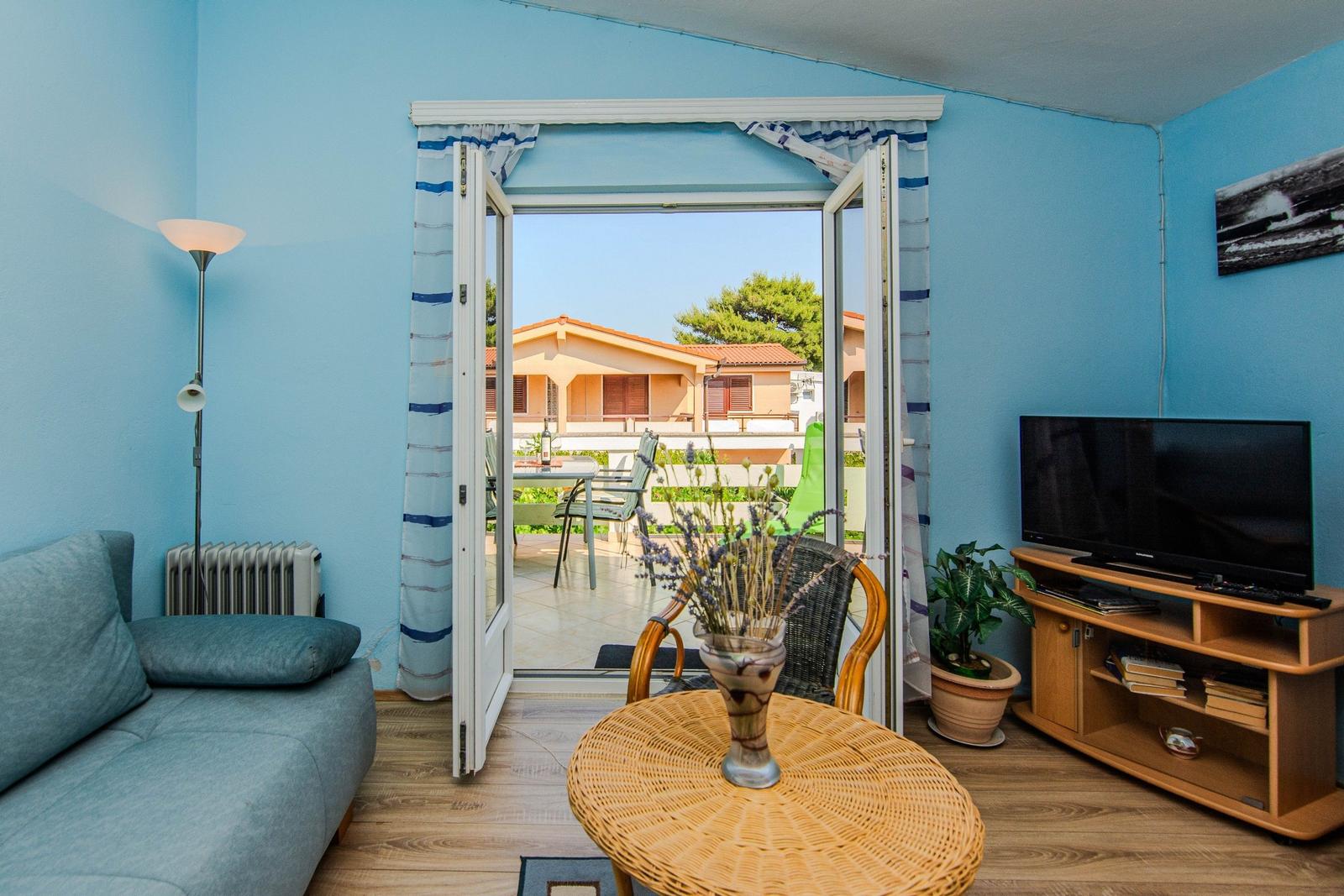 Living room with terrace, sofa, TV, and round table.