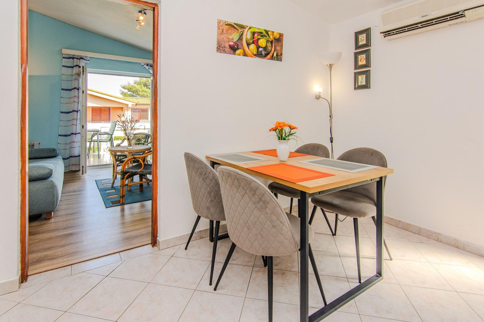 Dining area with table and chairs, view into living room with balcony.