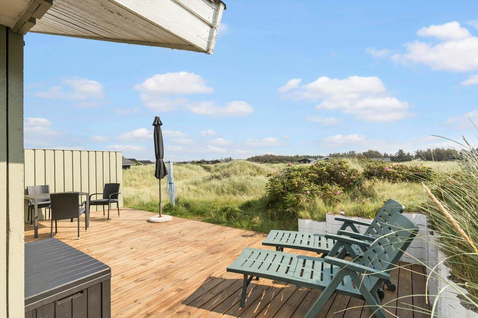 Terrasse mit Sitzgelegenheiten und Blick auf Dünen