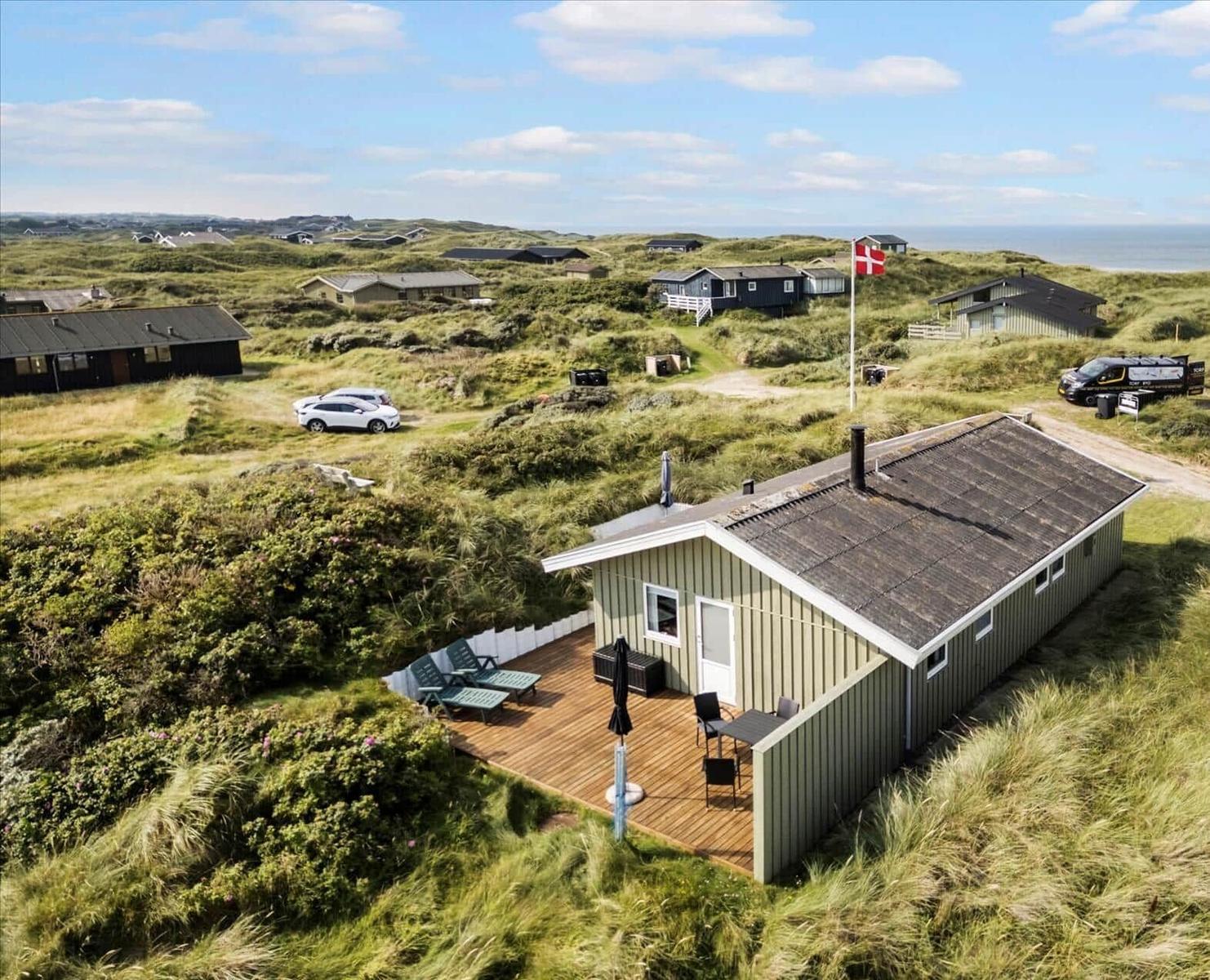 Holzhaus mit Terrasse und Blick auf die Dünen und das Meer.