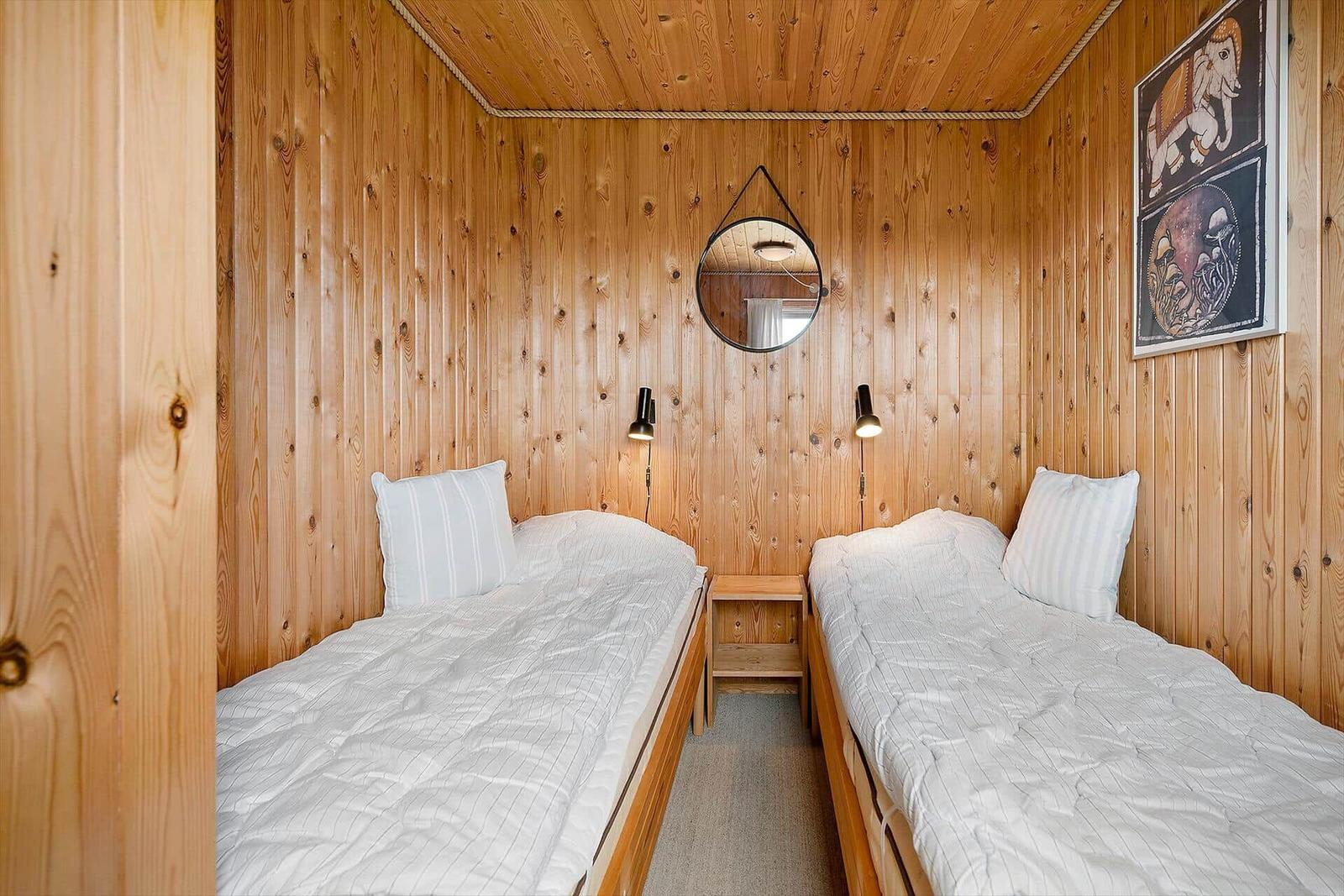 Zwei Betten mit weißen Laken, Holzwände und ein kleiner Nachttisch.