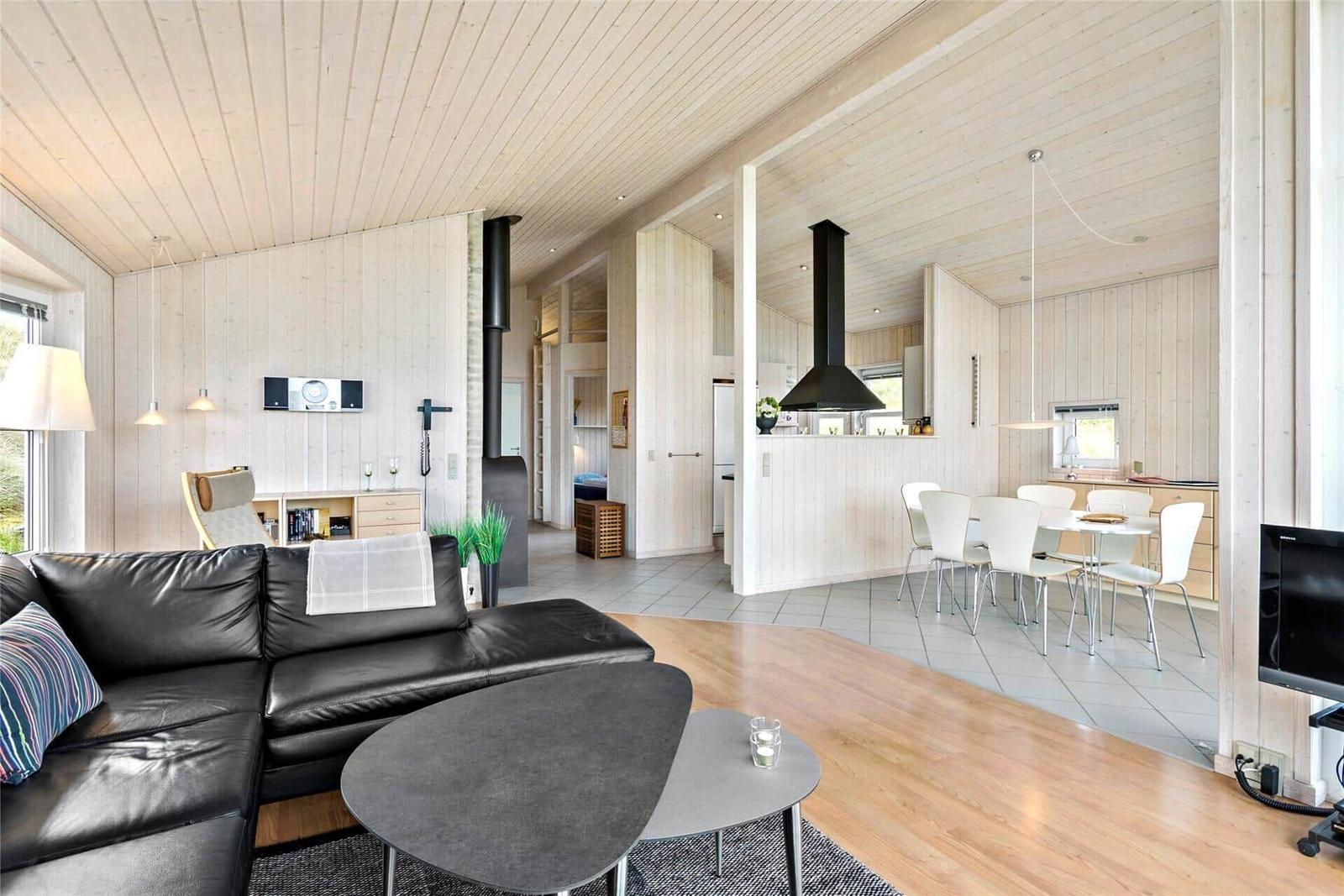 Wohnzimmer mit Sofa, Esstisch und Küche in Holzhaus.